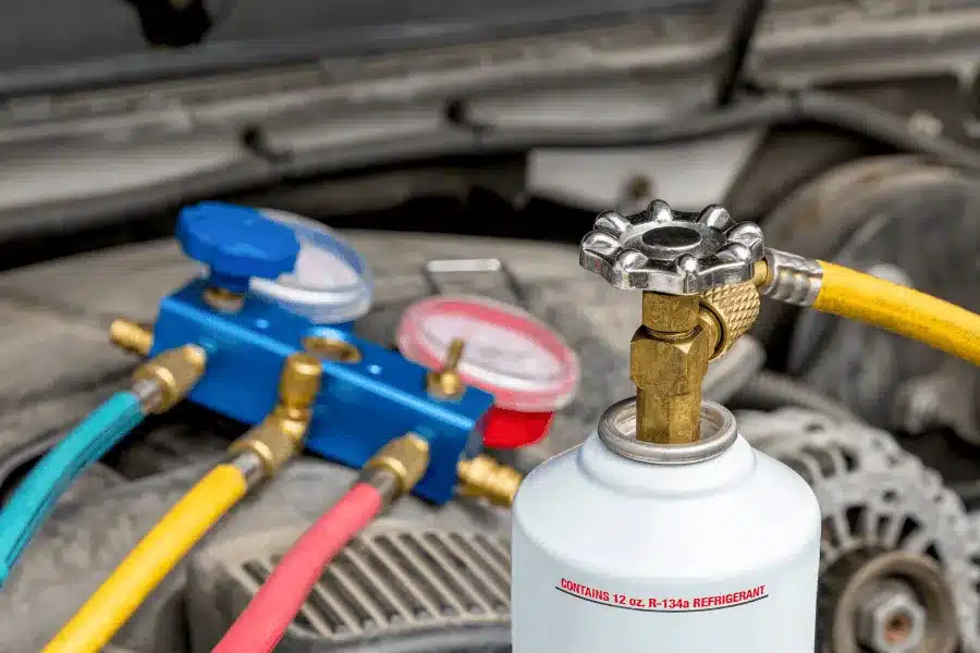 Auto air conditioning repair in Walnut Creek, CA, at N Service Auto Repair and Service. An image of an automotive A/C refrigerant gauge set and R-134a refrigerant connected to a vehicle during professional auto air conditioning diagnosis, recharge, and repair service.