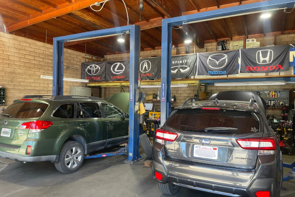 Vehicle maintenance, auto repair in Walnut Creek, CA at N Service Auto Repair and Service. Image of two Subaru vehicles positioned on service lifts inside the repair shop for inspection and maintenance.