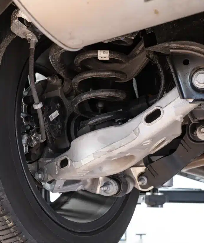 Suspension repair, auto repair in Walnut Creek, CA at N Service Auto Repair and Service. Close-up view of a cars rear suspension system, showing the coil spring, control arm, wheel, and various mechanical components.