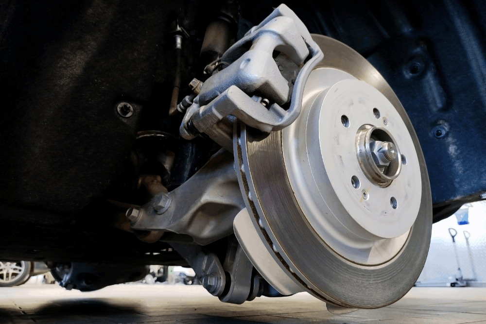 Brake inspection, auto repair in Walnut Creek, CA at N Service Auto Repair and Service. Image of a brake rotor, caliper, and suspension components with the wheel removed for inspection and maintenance.